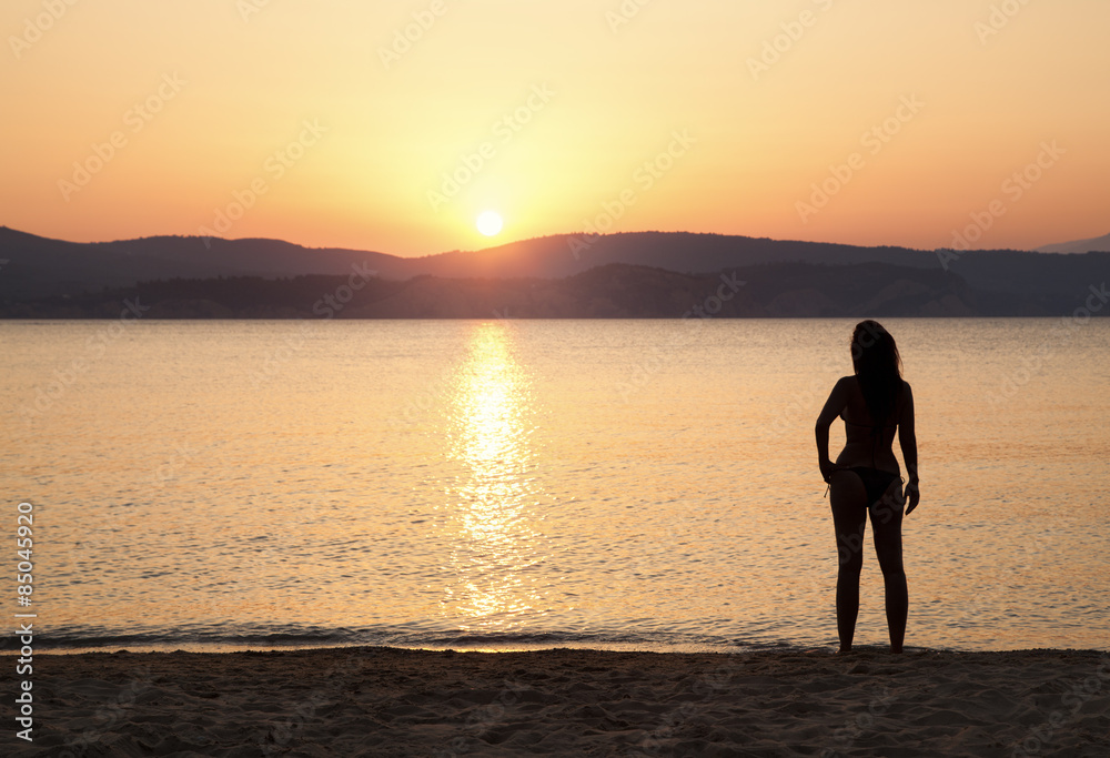 Silhouette einer schönen Frau bei Sonnenuntergang am Meer