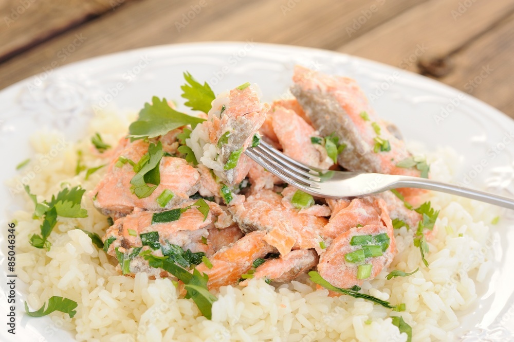 Salmon with rice, scallion and cilantro in white plate with fork