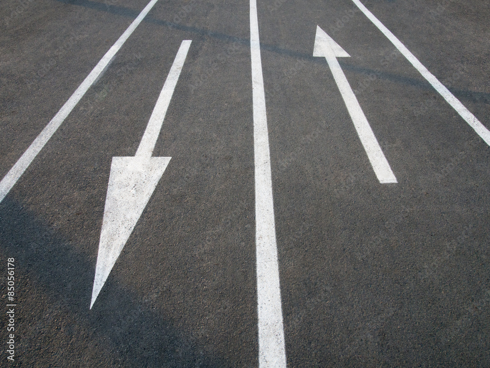 Directional arrow signs on the asphalt road.