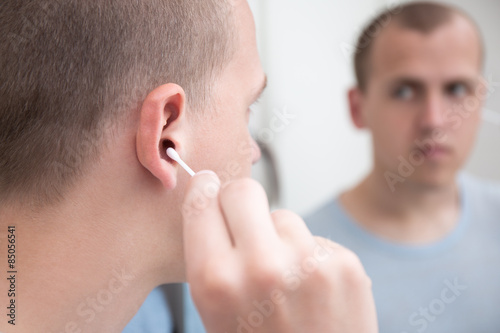 man cleaning his ear with a cotton swab