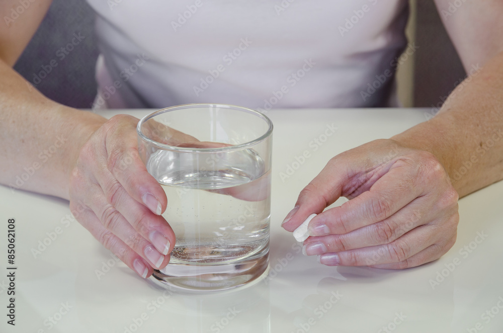 hand with pill and glass of water hand with pill and glass of water