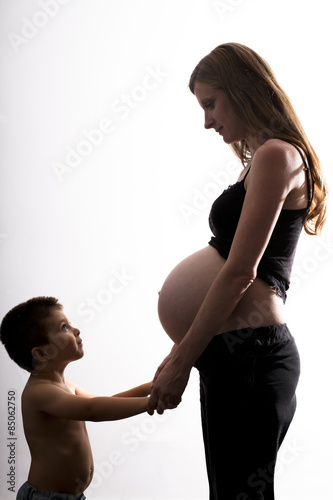 Niño y madre embarazada cogidos de las manos mirándose