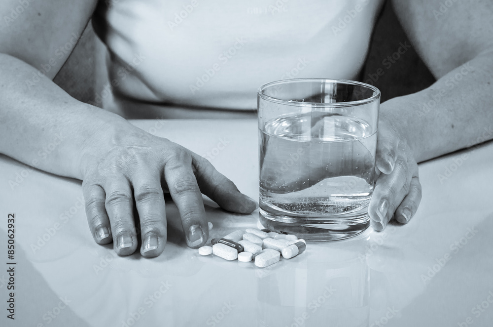hand with pill and glass of water hand with pill and glass of water