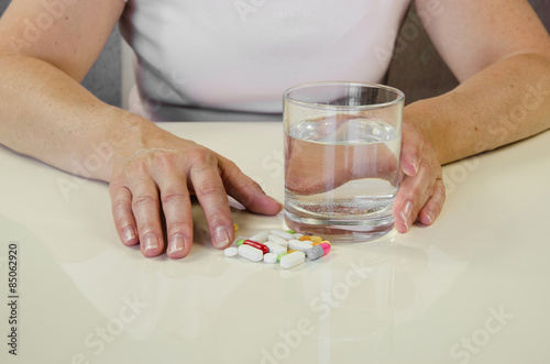 hand with pill and glass of water
