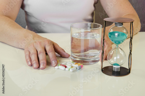 hand with pill, water and glass of water