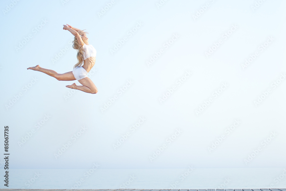 Beautiful fit woman  jumping at the beach near ocean