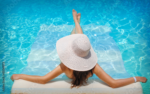 young woman in white hat resting in pool
