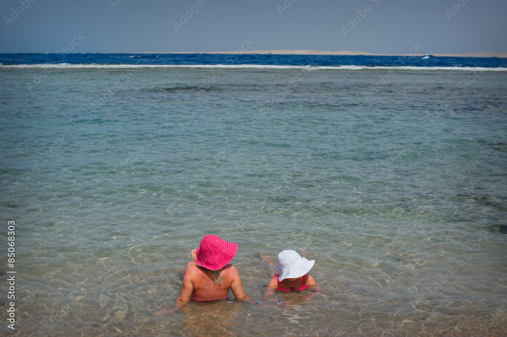 Two women in hats lie on the sea Two women in hats lie on the sea