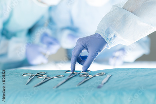 Close-up of scrub nurse taking medical instruments