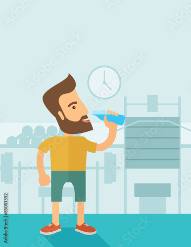 Gentleman drink a bottle of water while inside the gym.