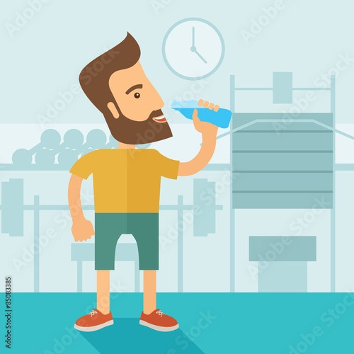 Gentleman drink a bottle of water while inside the gym.