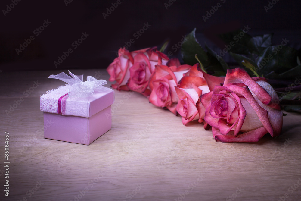 Beautiful roses and gift box on a wooden background