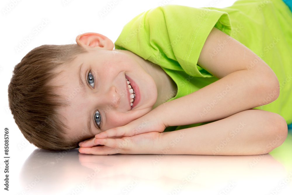 Fototapeta premium Smiling little boy lying on the floor placing your hands under y