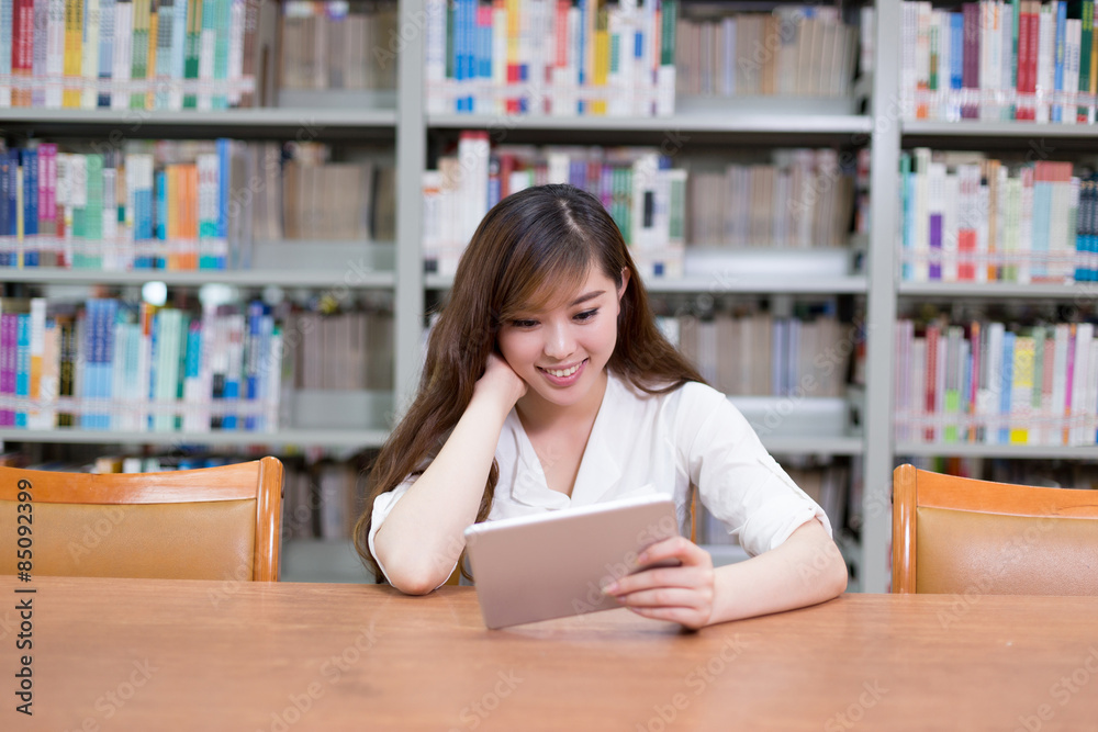 Beautiful asian female student using digital tablet in library Beautiful asian female student using digital tablet in library