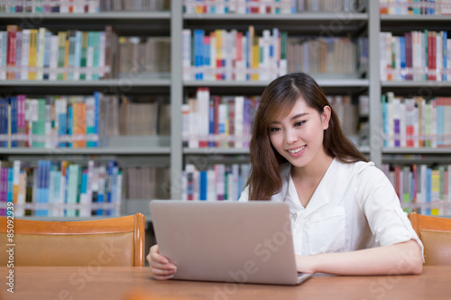 Beautiful asian female student using laptop for study in library