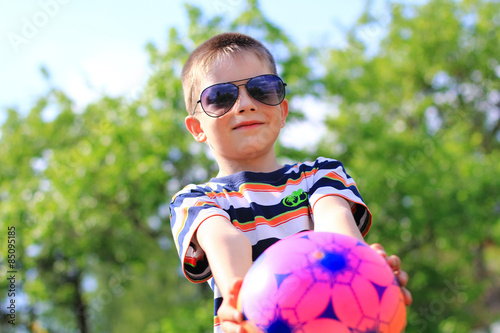 boy wearing sunglasses playing with a ball outdoors