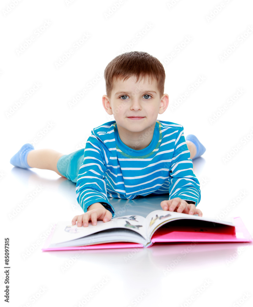 The boy in blue striped t-shirt lying on the floor and reading a The boy in blue striped t-shirt lying on the floor and reading a