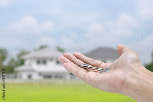Hand holding key on home background , house concept 