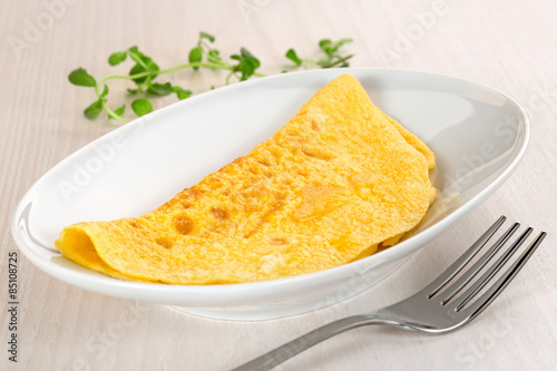 omelette plate and fork on wooden table photo