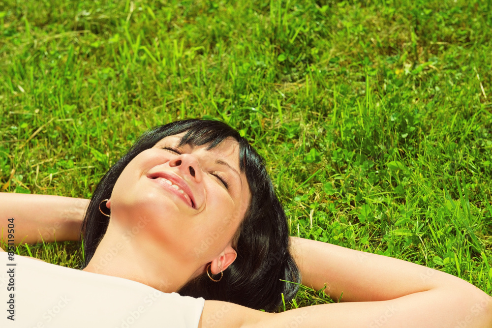 Beautiful happy young woman lying on the grass Beautiful happy young woman lying on the grass