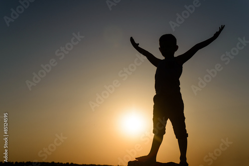Silhouette of Young Boy Standing with Open Arms