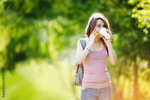 Woman wearing casual clothes talking on phone and drinking beverage