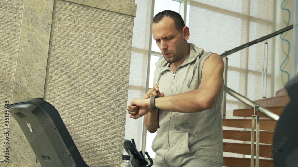 Man checking pulse on smartwatch on treadmill
