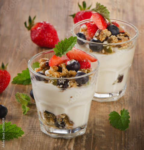Yogurt with Granola and fresh berries on a rustic wooden backgr
