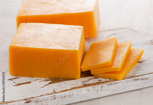 Cheddar Cheese on white wooden Cutting Board.