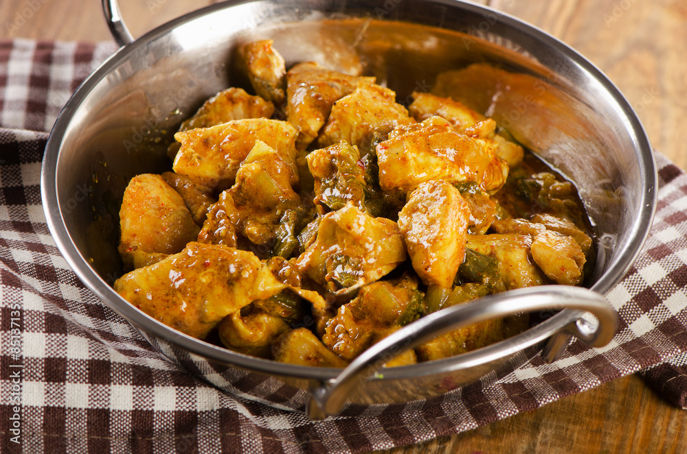 Chicken curry in balti dish on a wooden table. Chicken curry in balti dish on a wooden table.