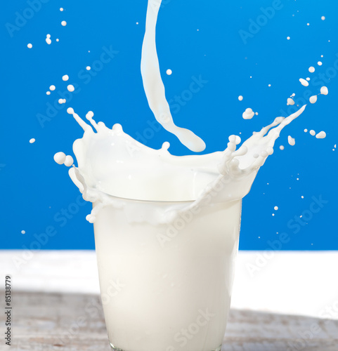 Splash of milk from the glass on a blue background