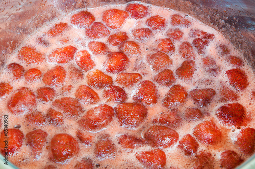 Cooking strawberry jam in a silver pot on the stove