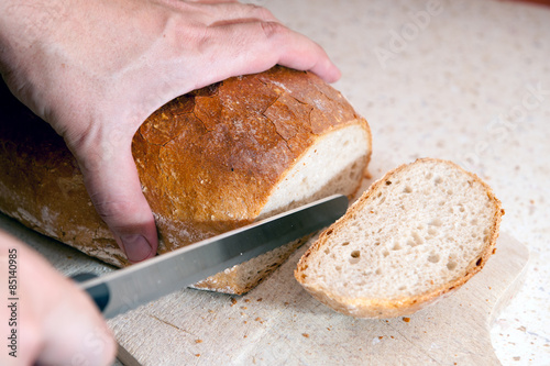 The fresh bread keen-witted a knife on a wooden plank in the kitchen