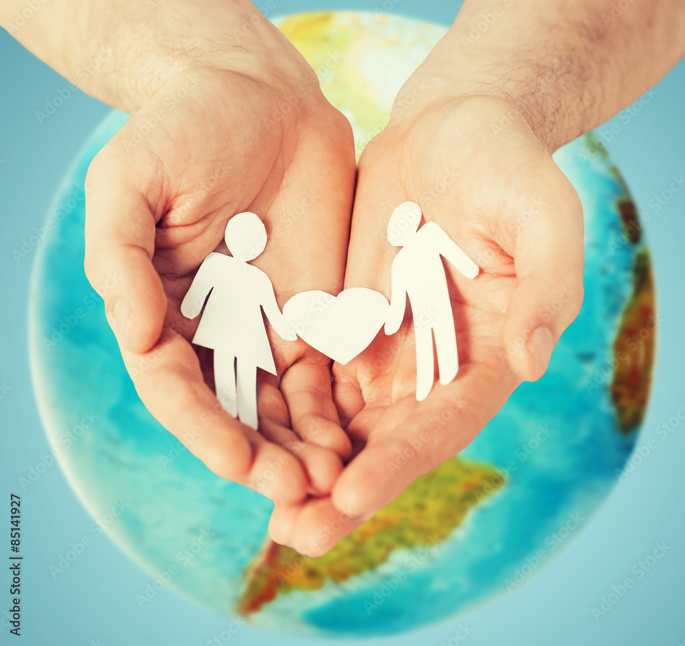 human hands holding paper couple over earth globe human hands holding paper couple over earth globe