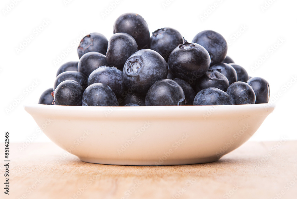 Blueberry fruits in a white bowl on wooden board background Blueberry fruits in a white bowl on wooden board background