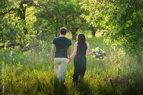 Young loving couple standing in the back with a large bouquet of flowers, love