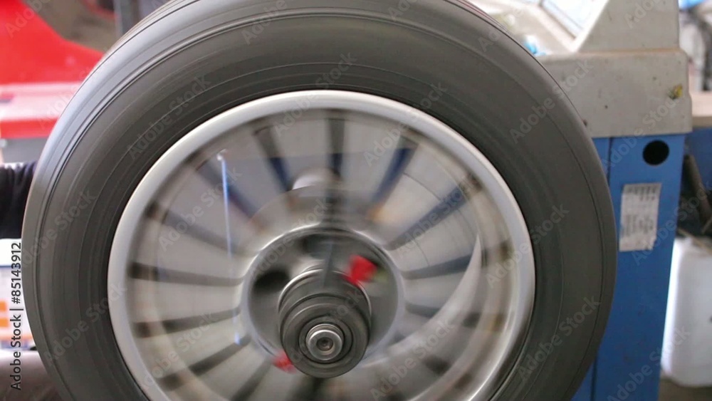 Mechanic in the service balances car wheel Mechanic in the service balances car wheel