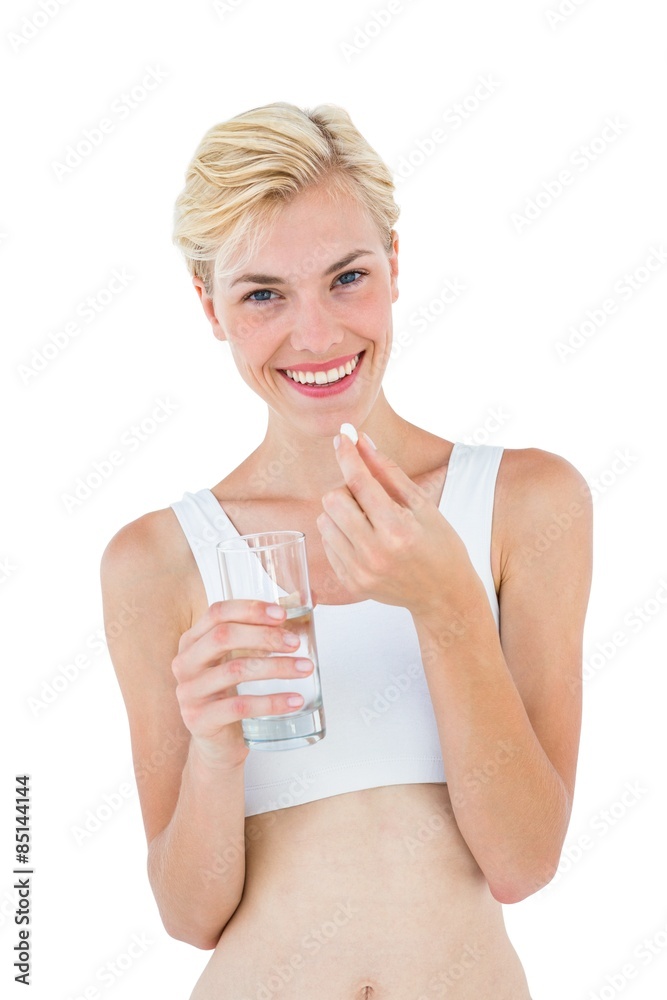Smiling blonde woman holding pill and looking at camera