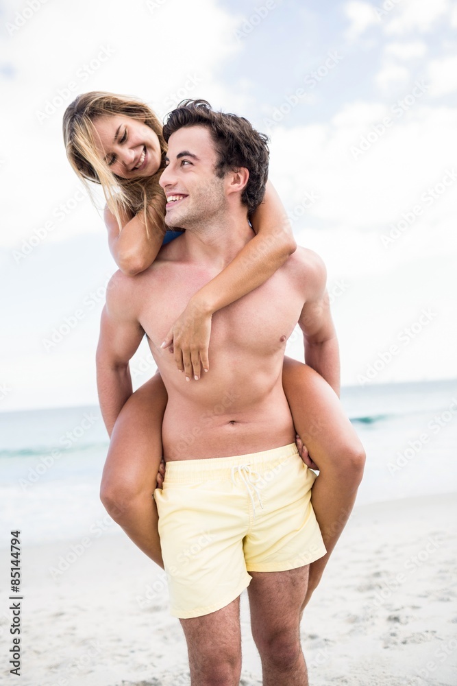 Handsome man giving piggy back to his girlfriend Handsome man giving piggy back to his girlfriend