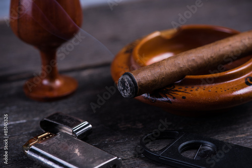 Cuban cigar in ashtray with lighter and cutter