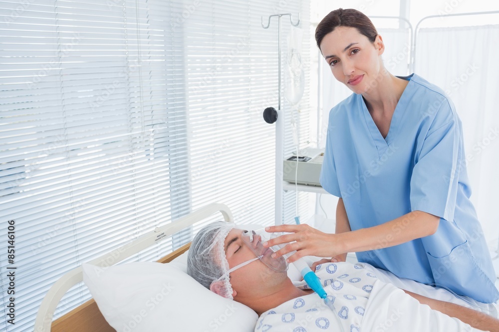 Obraz premium Smiling doctor holding patients oxygen mask