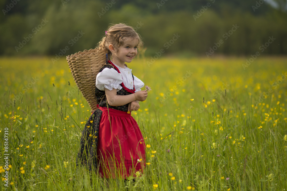 Bambina nel campo di fiori con gerla