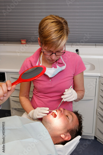 dental hygienist gives instruction to a man how to brush teeth