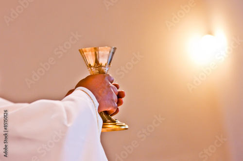 Close-up of a priest's hands holding a golden goblet for Holy Communion (Eucharist)