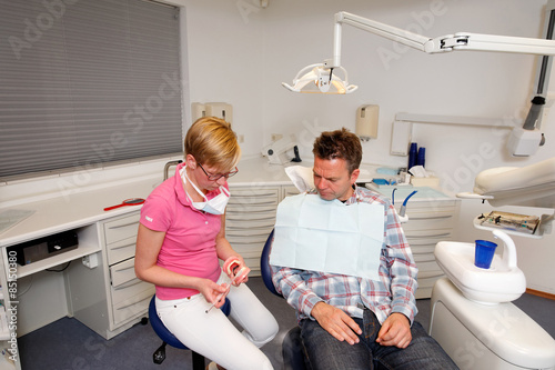 Photos man is getting instruction from a dental hygienist at her office