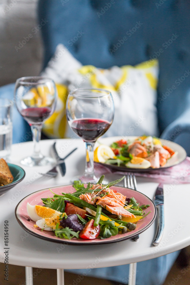 salad with salmon and verdure in plate on table with blue chair