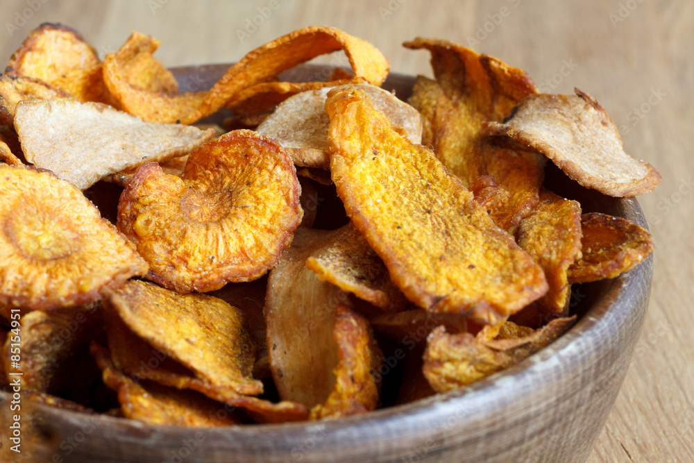Detail of fried carrot and parsnip chips in rustic wood bowl. Detail of fried carrot and parsnip chips in rustic wood bowl.
