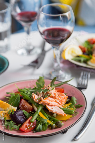 salad with salmon and verdure in plate on table with blue chair