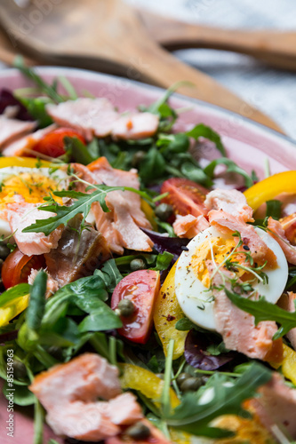 salad with salmon and verdure in pink plate on retro newspaper b