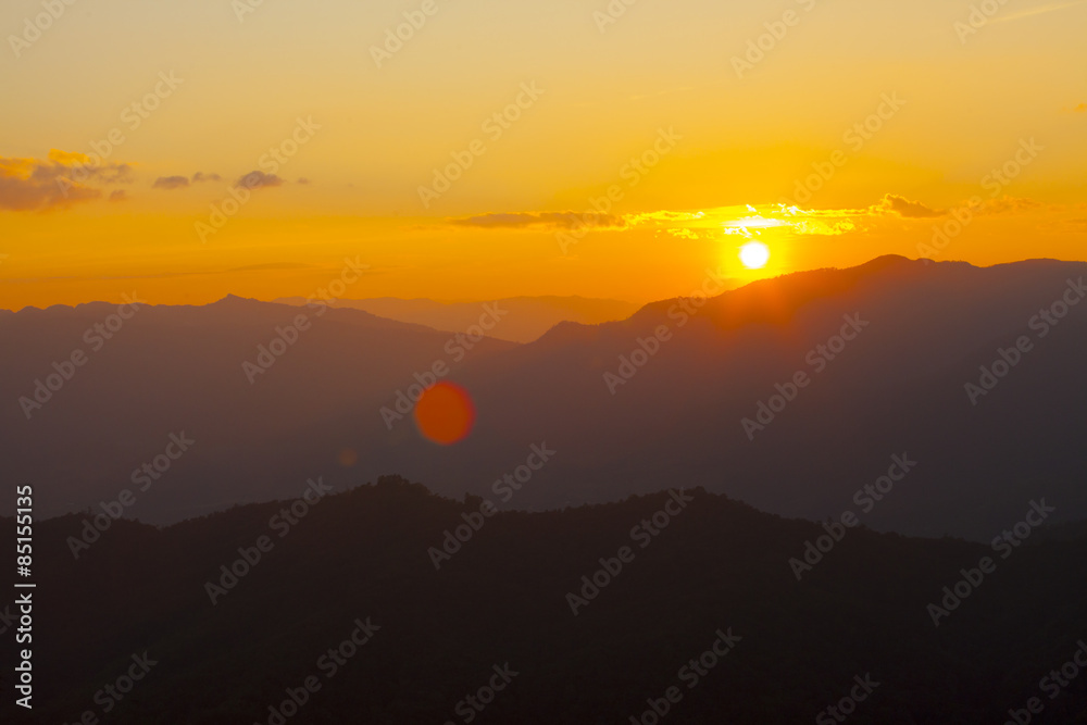 dramatic sky sun set over mountain with orange dramatic sky with lensflare